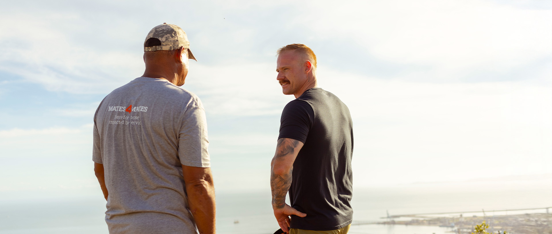 Two men standing together talking, looking out over the view of Townsville.