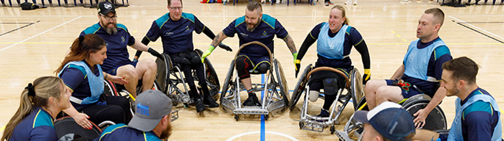 Wheelchair rugby team positioned in a circle, talking and preparing for the upcoming games at the Warrior Games.