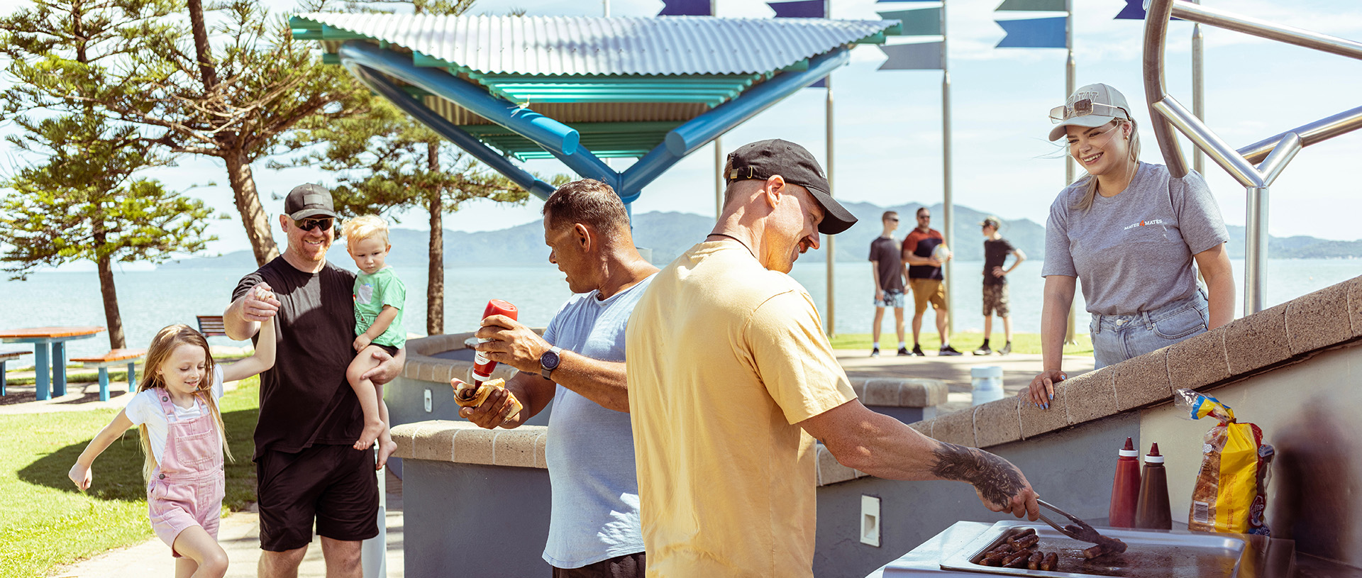 Group of people at an outdoor BBQ in the park on a sunny day.