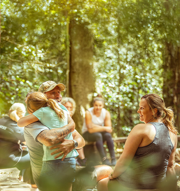 Family sitting together outdoors. Father and daughter embraced in a tight hug.